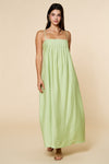 Woman wearing a light green maxi dress against a beige background