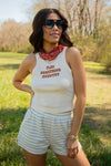 Woman wearing a sleeveless top with text and striped shorts in an outdoor setting
