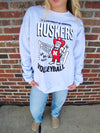 Person wearing a Nebraska Huskers volleyball sweatshirt in front of a brick wall