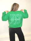 Person wearing a green sweatshirt with text on the back against a plain background