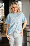 Woman wearing a light blue t-shirt with a graphic design in a casual indoor setting