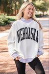 Person wearing a white 'NEBRASKA' sweatshirt outdoors.