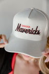 Gray cap with 'Omaha Mavericks' text held by a person against a neutral background