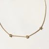 Gold necklace with 'GBR' pendants on a light beige background