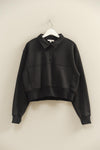Black sweater on a hanger against a beige wall